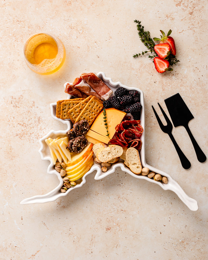 charcuterie board with cheese and cured meats in a alaska shaped serving tray