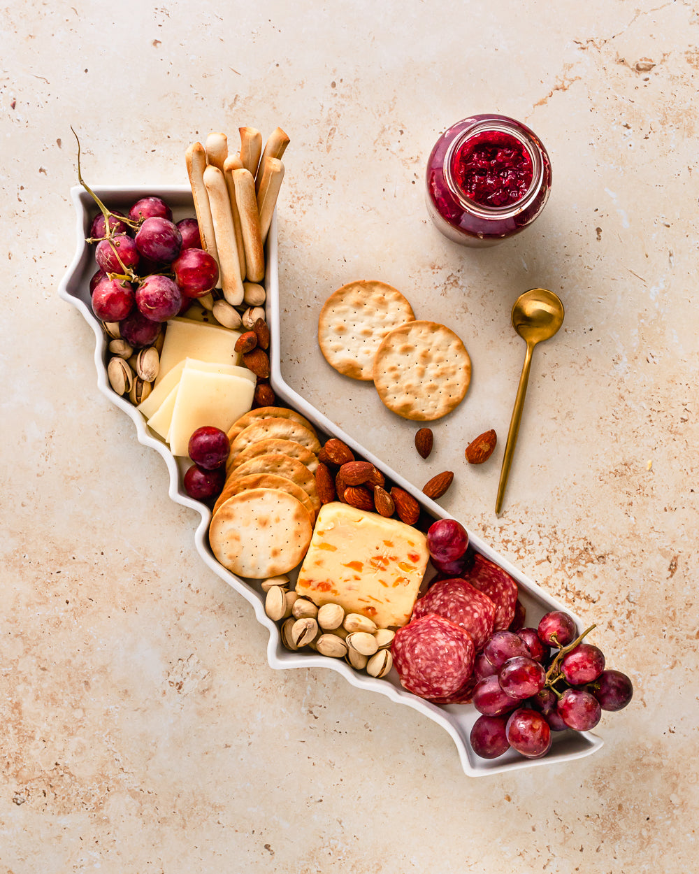 California state plate can be used as a cheese board or charctuerie tray. California with cheese, crackers, meat, and fruit. 